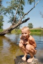 Happy wet boy sitting on rock in lake Royalty Free Stock Photo