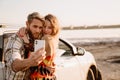 Happy white couple taking selfie photo by car while walking at seashore Royalty Free Stock Photo