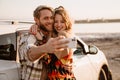 Happy white couple taking selfie photo by car while walking at seashore Royalty Free Stock Photo