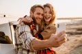 Happy white couple taking selfie photo by car while walking at seashore Royalty Free Stock Photo