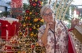 Happy white-haired senior woman doing shopping for Christmas in a mall, standing near Christmas decorations holding bags with Royalty Free Stock Photo