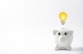 Happy white Piggy Bank and Light bulb in close-up and coins stack on white background, Royalty Free Stock Photo