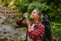 Happy woman taking photo on camera while hiking in forest