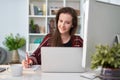 Happy white young business woman working at home with laptop computer, coffee, papers on desk Royalty Free Stock Photo