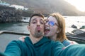 Happy wife with glasses laughing, giving hug with tenderness her latin husband, sending kiss to camera, flirting in coast. Friends Royalty Free Stock Photo