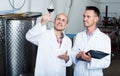 Happy winery workers standing with glass of wine Royalty Free Stock Photo