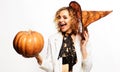 Happy winking girl in witch hat with pumpkin. Halloween party. Smiling woman with Jack-o-lantern. Royalty Free Stock Photo