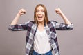 Happy winner! Close-up of emotional young attractive woman with keeping hands in fists, isolated on grey background. Surprised Royalty Free Stock Photo