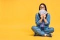 Happy winner! Portrait of a cheerful young woman holding money banknotes and celebrating victory isolated over yellow background. Royalty Free Stock Photo