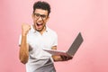 Happy winner! Portrait of happy young afroamerican man using laptop comruter and checkin isolated against pink, celebration