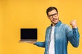 Happy winner! Smiling businessman pointing finger on blank laptop screen. Looking at camera