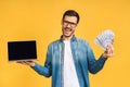 Happy winner! Smiling businessman pointing finger on blank laptop screen isolated over yellow background. Looking at camera.