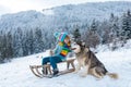 Happy winter child boy. Dog alaskan malamute and kid in snow winter, Austria or Canada. Royalty Free Stock Photo