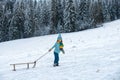 Happy winter child sledding in winter snowy forest. Kids with sled, sleigh in snow. Little boy enjoy the holiday. Royalty Free Stock Photo