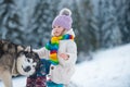 Happy winter kid girl. Husky dog with child in snow on winter forest background.