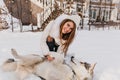 Happy winter time of amazing smiling girl plying with husky dog in snow. Charming young woman with long brunette hair Royalty Free Stock Photo