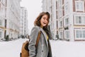 Happy winter time in big city of charming girl walking on street in coat with backpack. Enjoying snowfall, expressing Royalty Free Stock Photo