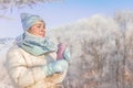 Happy winter woman holding thermo mug with hot beverage walking outdoor natural frozen park Royalty Free Stock Photo