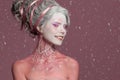 Happy winter woman with snowflake on her face in snow on pink background. Creative makeup, halloween party stage character Royalty Free Stock Photo