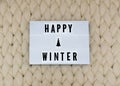 HAPPY WINTER word on lightbox on knit background. Cozy compozition. Knit background. Royalty Free Stock Photo