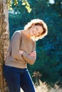 Happy woman against tree standing with arms crossed