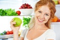 Happy woman with apple and open refrigerator with fruits, vegeta