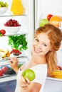 Happy woman with apple and open refrigerator with fruits, vegetables and healthy food