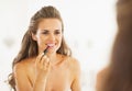 Happy woman applying lipstick in bathroom Royalty Free Stock Photo