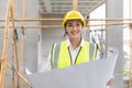 Happy woman architect home builder project manager work in construction site with blueprint floor plan looking camera smiling