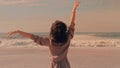 Happy woman with arms raised up at the beach enjoying sea view