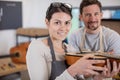 happy woman as luthier apprentice holds guitar spare for reparation
