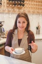 Happy woman barista offering coffee to customer at cafe