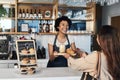 Happy woman, barista and serving customer at cafe for service, payment or order on counter at coffee shop. African Royalty Free Stock Photo