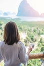 Happy woman in bathrobe holding hot coffee cup or tea mug after waking up and enjoy Phang Nga bay view point, Tourist relaxing in Royalty Free Stock Photo