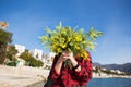 Happy woman on the beach with a bouquet of mimosa flowers. Royalty Free Stock Photo
