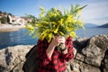 Happy woman on the beach with a bouquet of mimosa flowers. Royalty Free Stock Photo