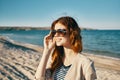 happy woman on the beach near the sea in the mountains glasses on the face red hair model landscape Royalty Free Stock Photo