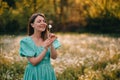 Happy woman beautiful blowing on dandelion in park. Girl in vintage blue dress. Wishing, joy concept. Springtime Royalty Free Stock Photo