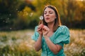 Happy woman beautiful blowing on dandelion in park. Girl in vintage blue dress. Wishing, joy concept. Springtime Royalty Free Stock Photo