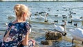 Happy woman in a beautiful dress with a charismatic appearance against the background of birds of swans on the lake in