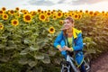 Happy woman bicyclist riding bicycle in sunflower field holding water bottle. Summer sport activity. Healthy lifestyle Royalty Free Stock Photo