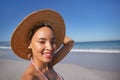 Happy woman in bikini and hat looking at camera on beach in the sunshine Royalty Free Stock Photo