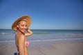 Happy woman in bikini and hat looking at camera on beach in the sunshine Royalty Free Stock Photo