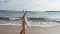 Happy woman in bikini and shirt walking on the beach near the ocean and raising hand. Young beautiful girl enjoying life Royalty Free Stock Photo