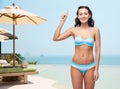 Happy woman in bikini swimsuit pointing finger up