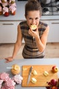 Happy woman biting into apple quarter in kitchen Royalty Free Stock Photo