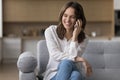 Happy young woman blab on the smartphone seated on couch Royalty Free Stock Photo