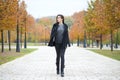 Happy woman in black coat walking autumn street