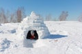 Happy woman in a black jacket in an igloo on a snow Royalty Free Stock Photo