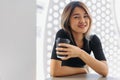 Happy woman in black t-shirt sipping hot coffee in white coffee shop. Royalty Free Stock Photo